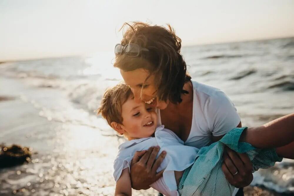 mom holding son playing on the beach